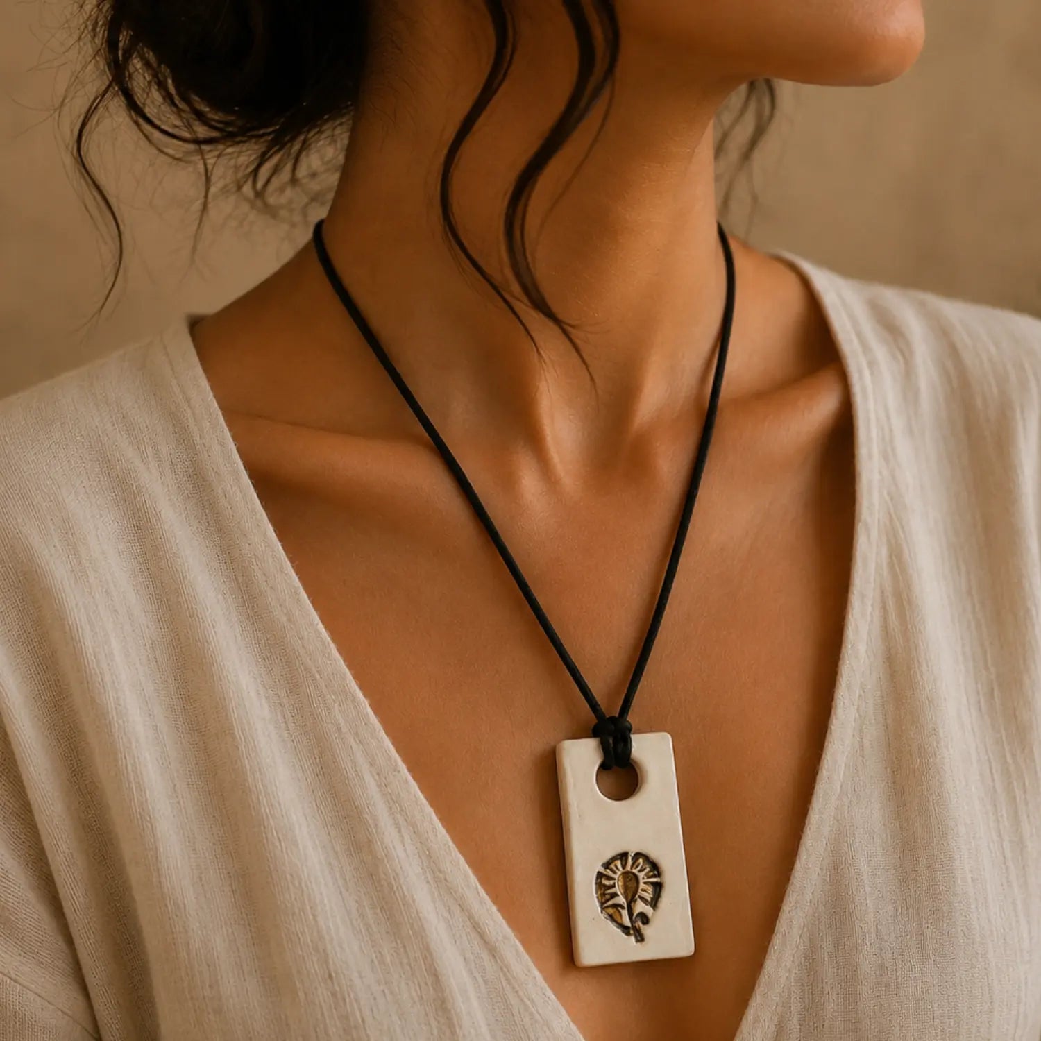 Handmade white ceramic pendant with golden bloom motif on black cord -- Earthan Jaipur