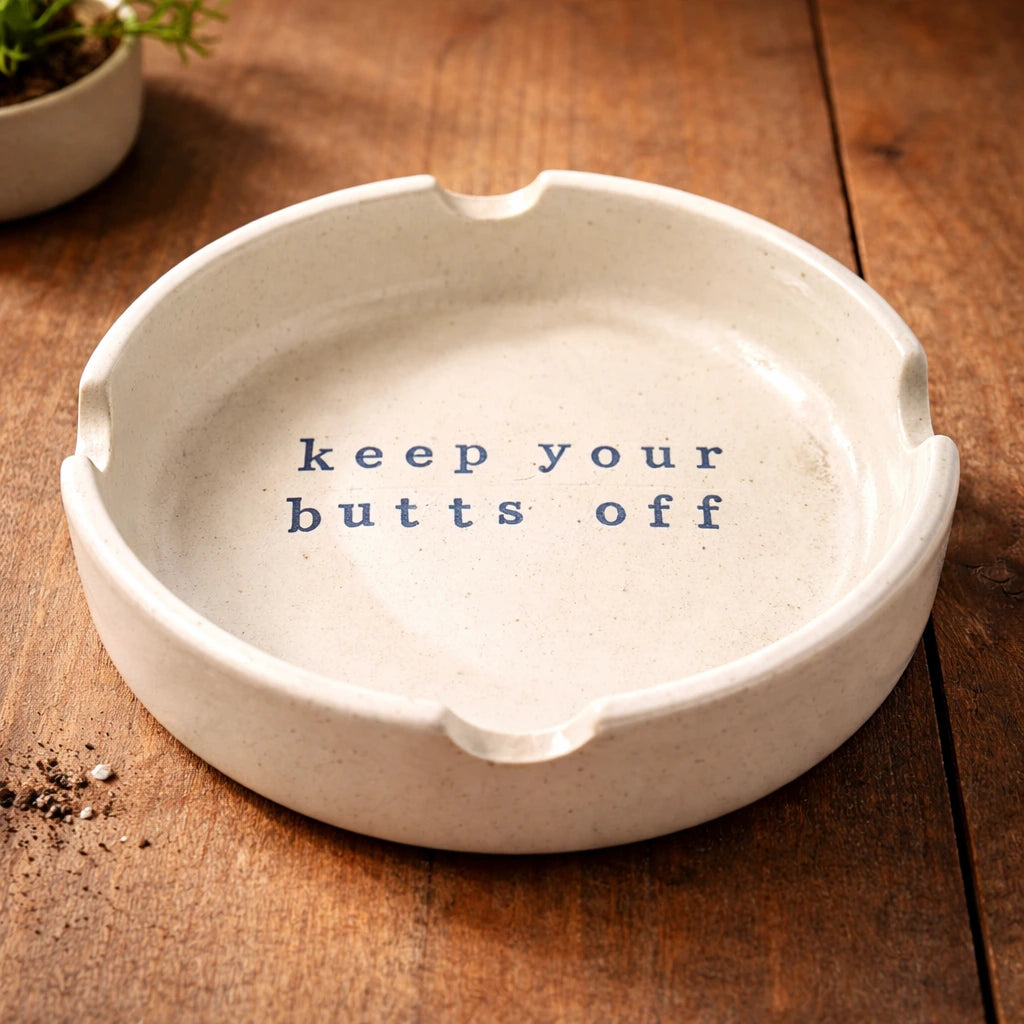 Ceramic Ashtray with quirky message 'keep your butts off', handcrafted ceramic design on wooden table.